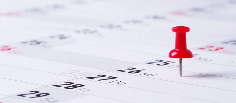 Roter Pin steckt in Kalender