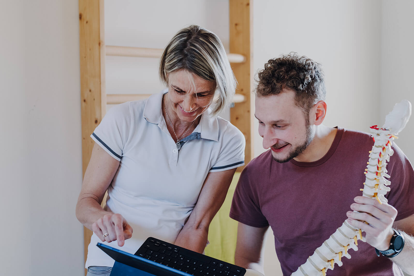 Physiotherapeutin erklärt einem Patienten myofasziale Triggerpunkte auf einem Tablet