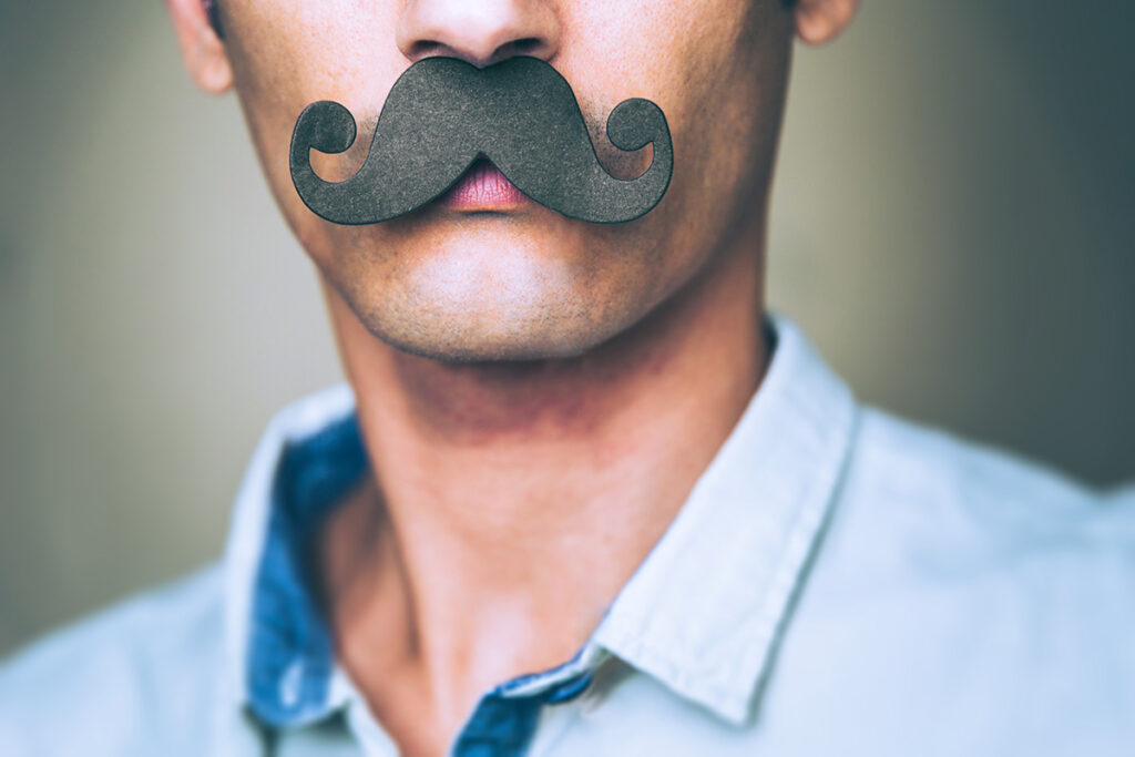 Mann mit falschem Schnurrbart für Movember
