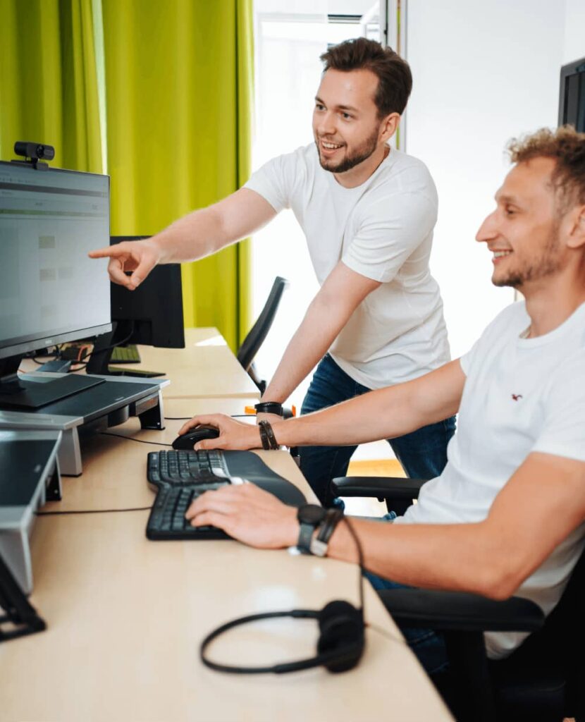 Zwei fröhliche Männer arbeiten am Computer